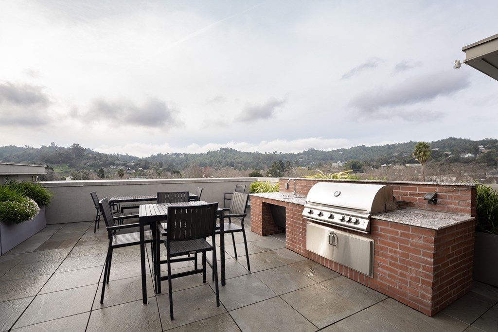 a patio with a barbecue grill and a table and chairs