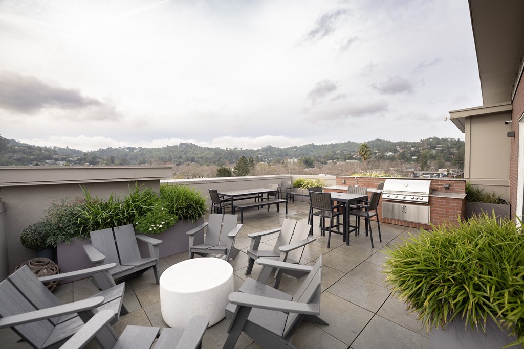 a rooftop patio with tables and chairs and a grill