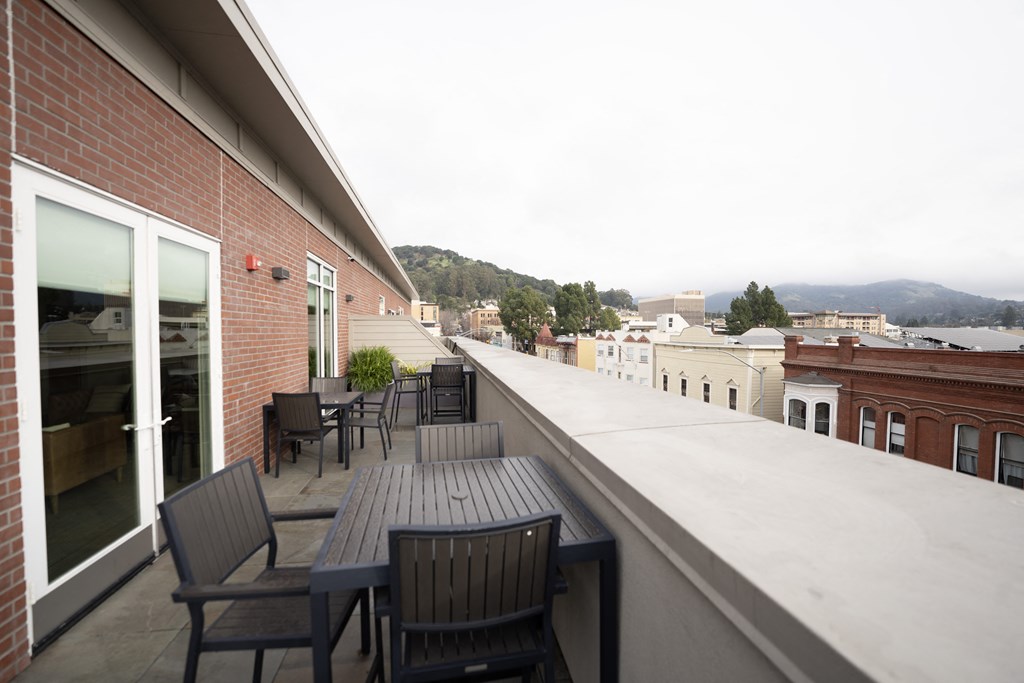 a balcony with tables and chairs on a roof