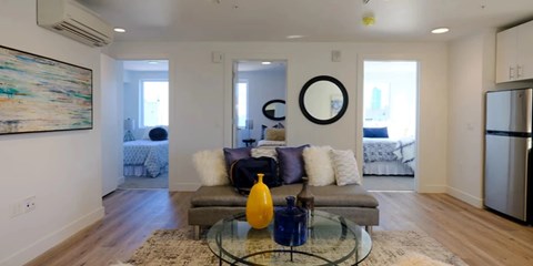 A modern living room with a grey couch and a glass coffee table.