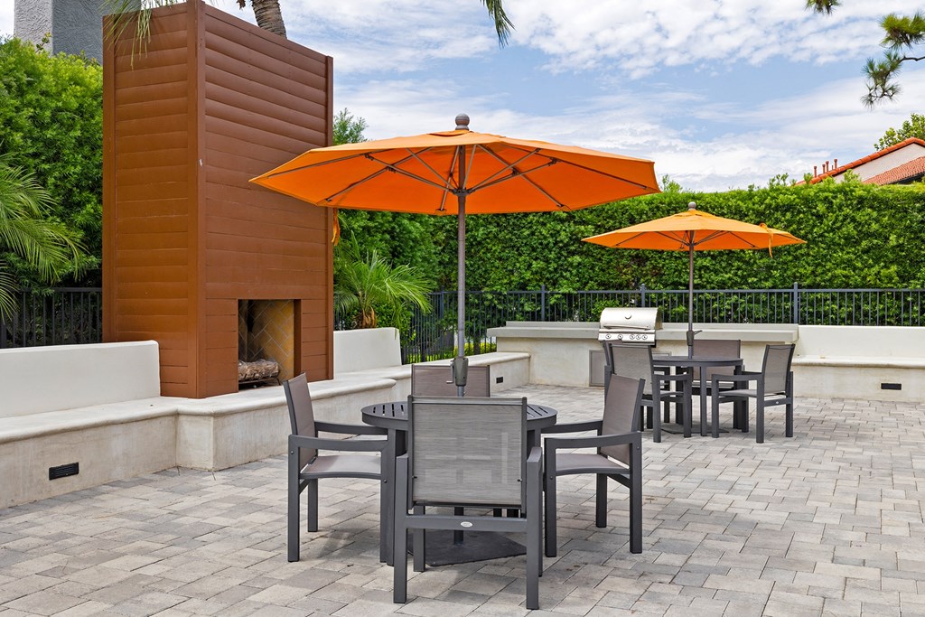a patio with a fire place and tables with umbrellas