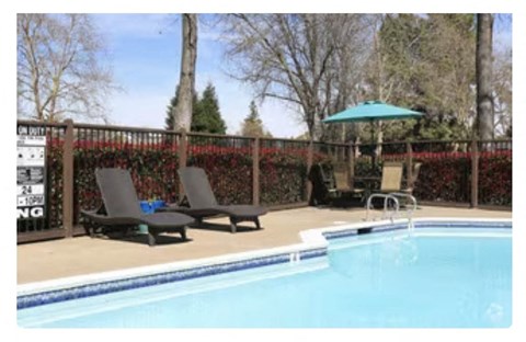 a swimming pool with two lounge chairs and an umbrella