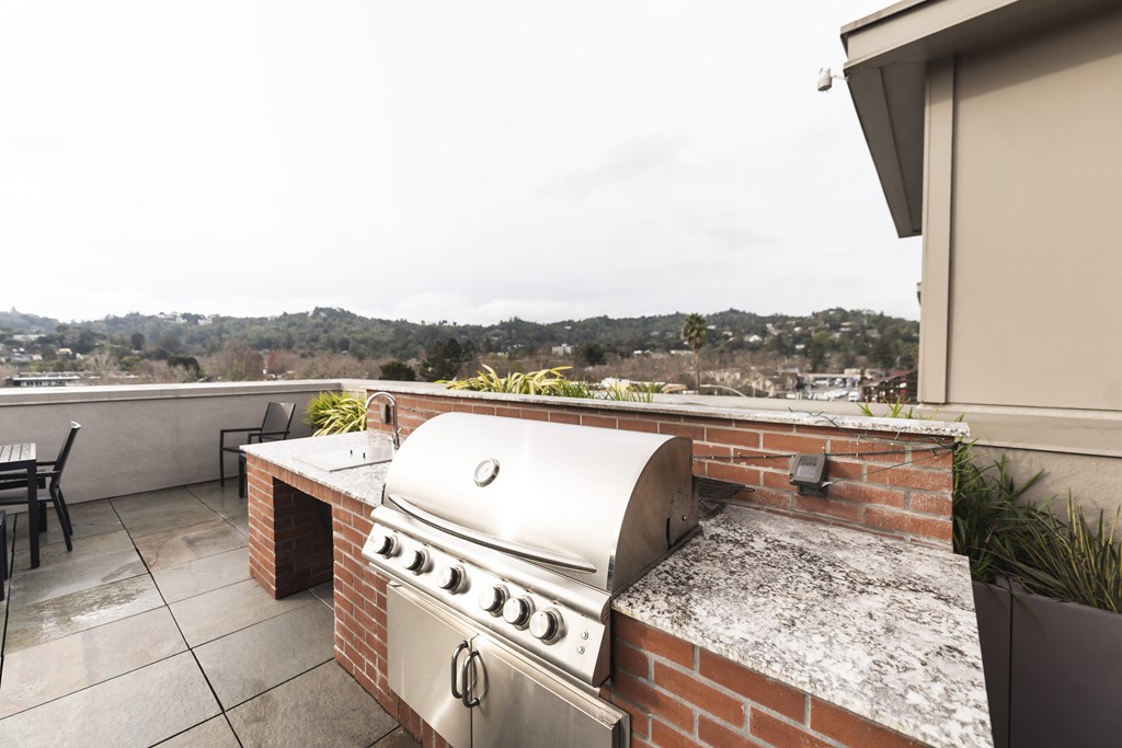 a outdoor kitchen with a grill and a table with chairs