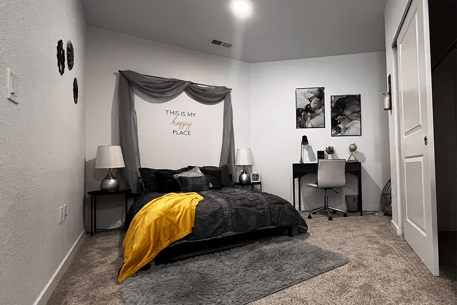 One-BR Apartments in Sparks, NV - The Deco - Bedroom with Carpet Flooring, a Ceiling Light, a Large Bed, and Stylish Decor