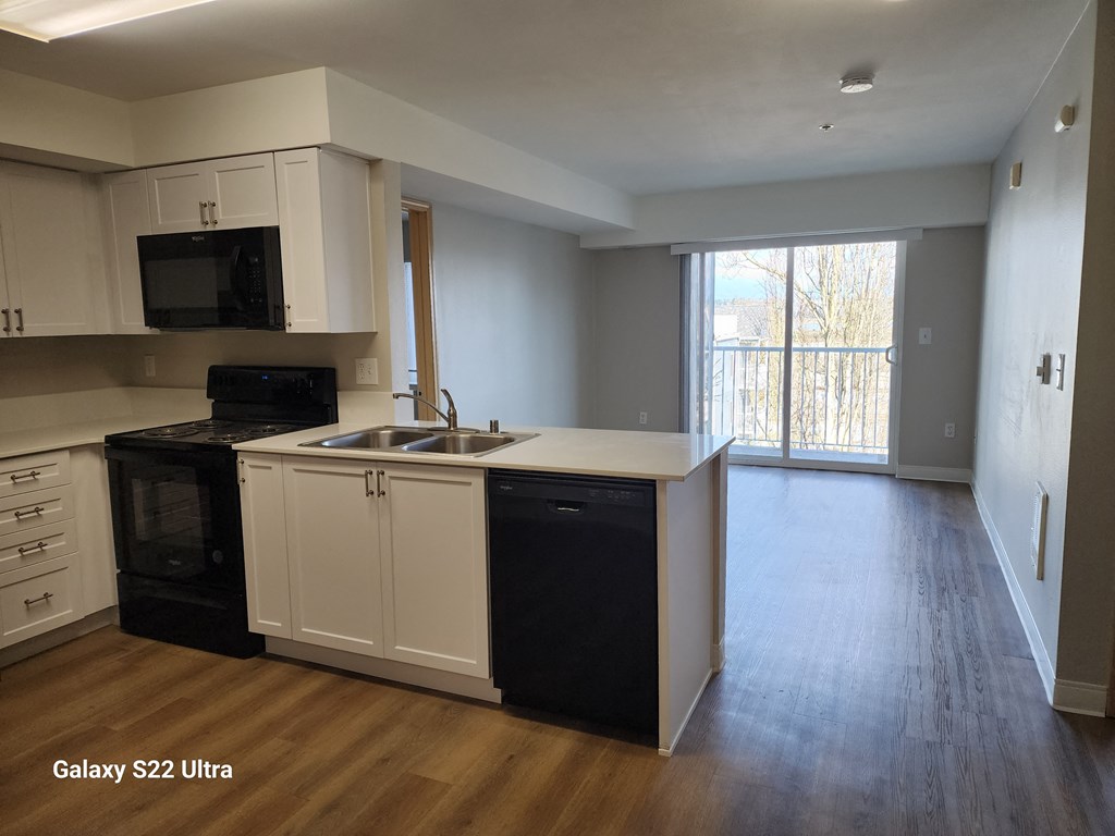 A kitchen with black appliances and white cabinets  at Everett Senior Community, 98201