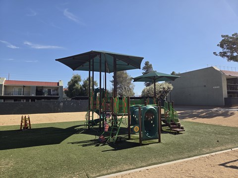 A playground with a green canopy and a slide.