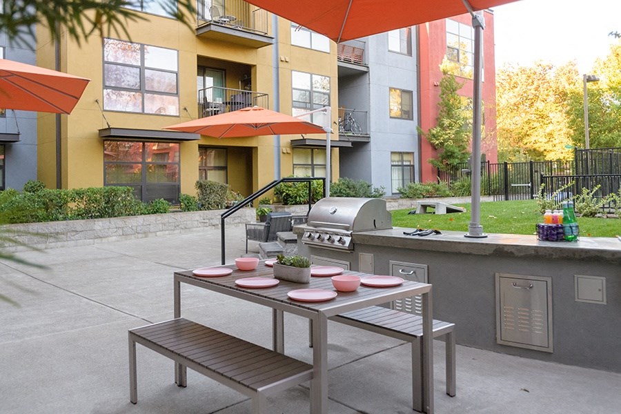  BBQ Area with Grilling Station, Table and Benches, Grassy Lawn with Cornhole Board, and Building Exterior in the Background  at FREMONT MEWS, California, 95814