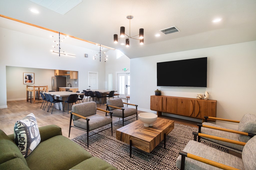 a living room and dining room with a large tv on the wall