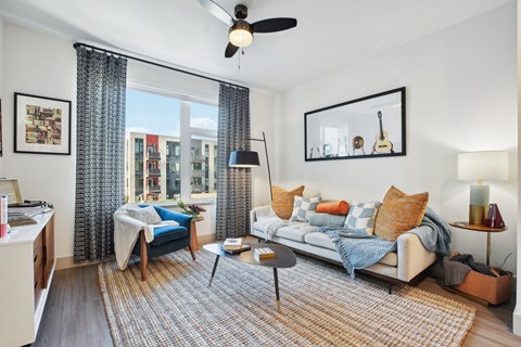A living room with a blue couch and a rug.