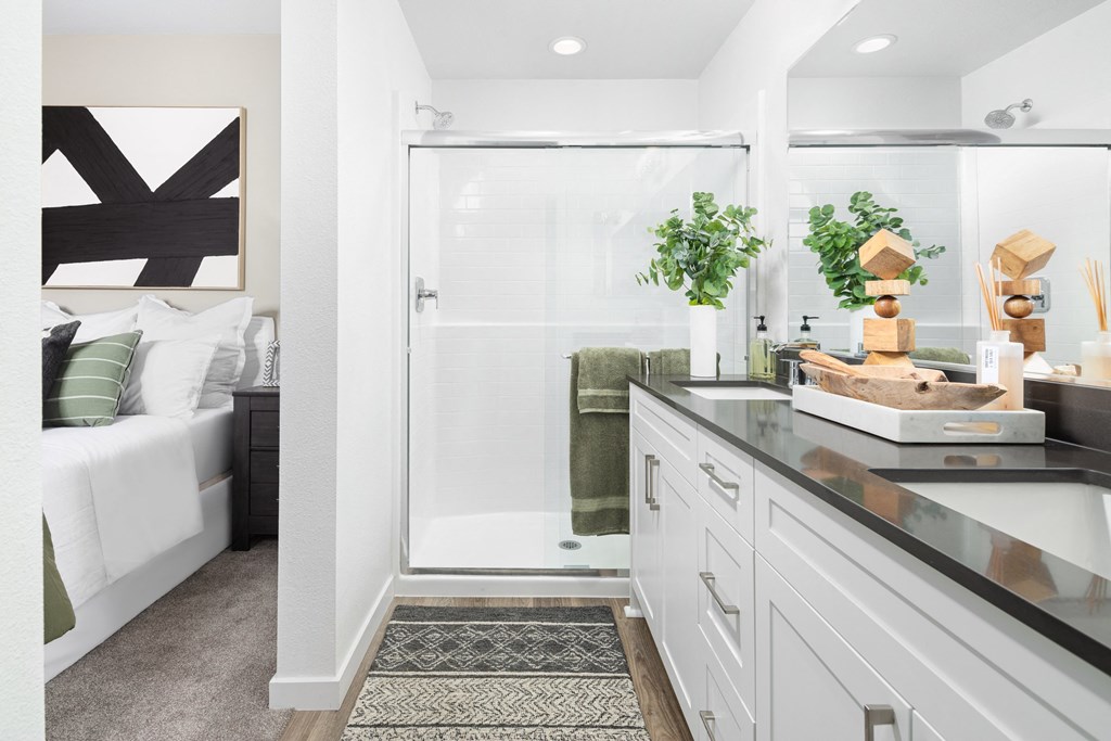 a bathroom with a shower and a bed in the background