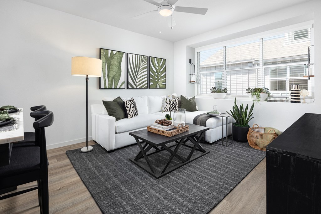 2-Bedroom Houses for Rent in Roseville, CA - Solstice at Fiddyment Ranch - Living Room with Wood-Style Flooring, Area Rug, Sectional Couch, Coffee Table, Cabinet, TV, Ceiling Fan, Patio Door, and Large Window with Blinds