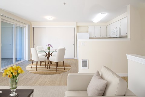 A living room with a white couch and a glass table with flowers on it.