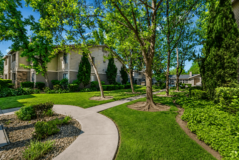 A tree in a grassy area in front of a building.