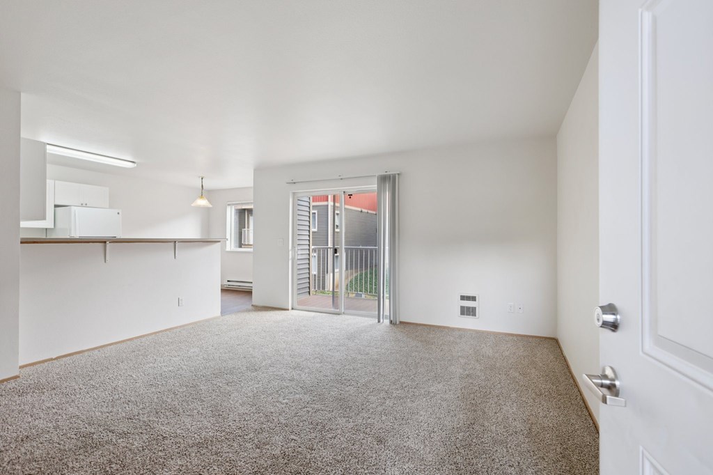 A room with a carpeted floor and a sliding glass door leading to a balcony.at The Timbers by Vintage, Arlington, 98223