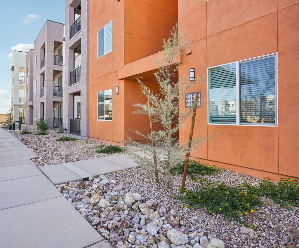 A modern apartment building with a sidewalk and landscaping in front.at Cottonwood Ranch, Arizona, 85122
