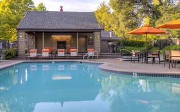 a pool with chairs and umbrellas next to a building