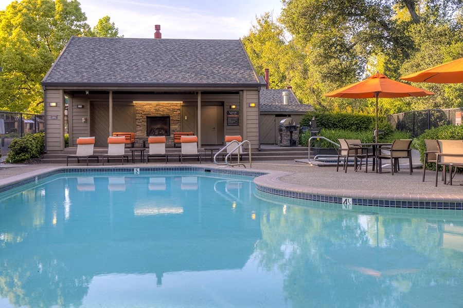a pool with chairs and umbrellas next to a building