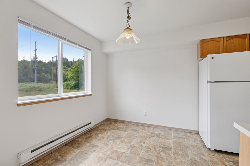 A room with a window, a tiled floor, and a white refrigerator.at The Timbers by Vintage, Washington