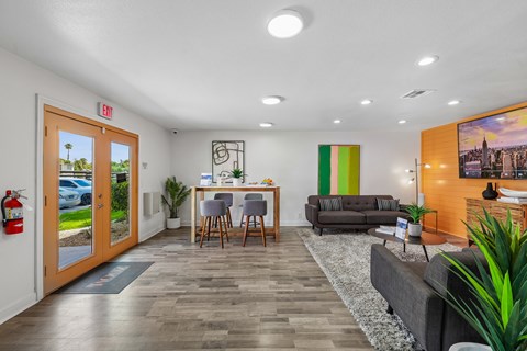 A living room with a grey couch and a wooden dining table.
