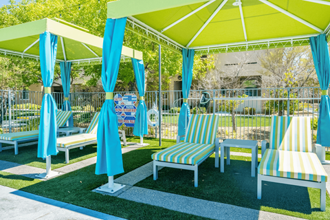 A sunny day at the park with blue umbrellas and striped chairs.
