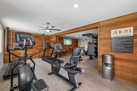 A gym with a variety of equipment including treadmills, stationary bikes, and elliptical machines.