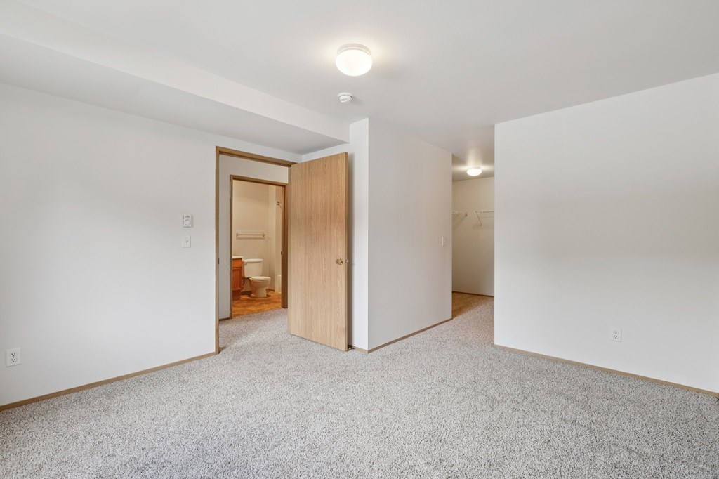 A room with a carpeted floor and a doorway leading to another room.at The Timbers by Vintage, Arlington, 98223