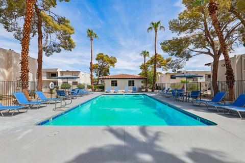A swimming pool surrounded by palm trees and lounge chairs.