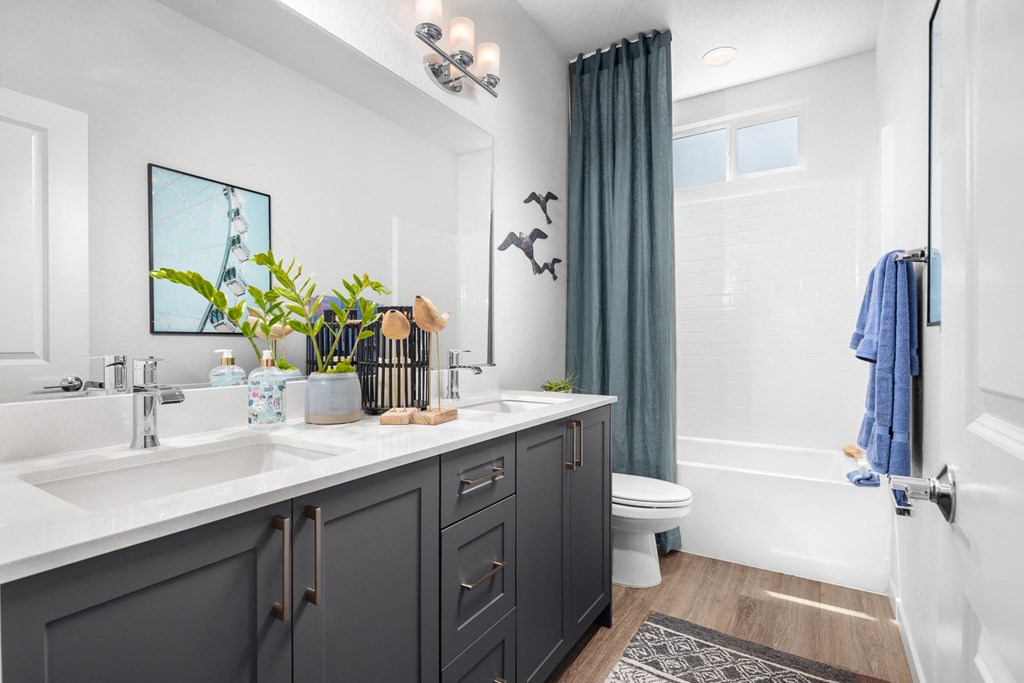 a bathroom with gray cabinets and a white bathtub