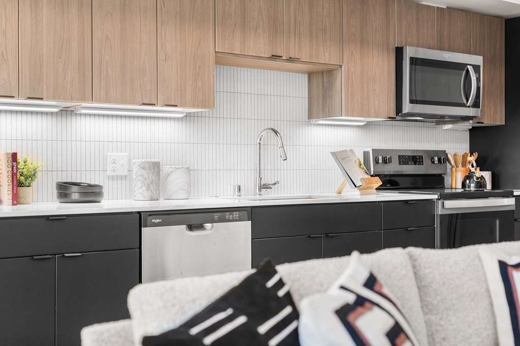 A modern kitchen with black cabinets and a white backsplash at Two 10 by Vintage, Washington 98133