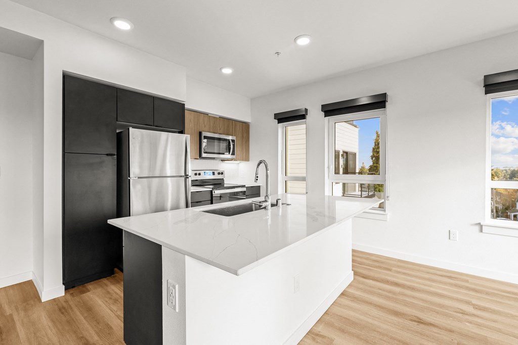 A modern kitchen with a black refrigerator and white countertops at Two 10 by Vintage, Shoreline, WA 98133