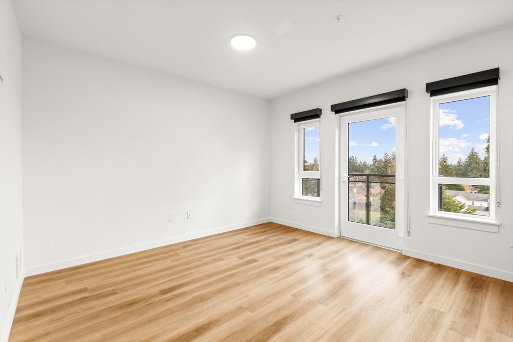 A room with wooden floors and three windows at Two 10 by Vintage, Shoreline, WA 98133