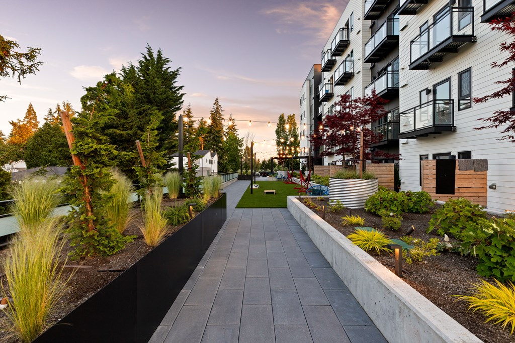 A long, narrow walkway separates two buildings with a landscaped area on either side  at Two 10 by Vintage, Shoreline, WA, 98133