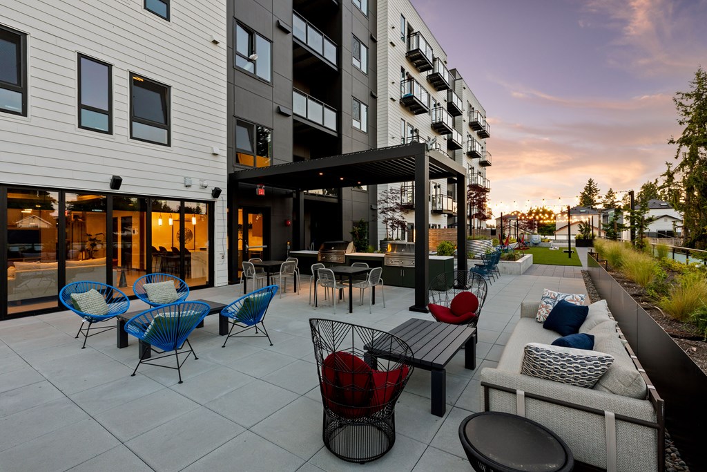 A patio with a table and chairs is surrounded by apartment buildings  at Two 10 by Vintage, 98133
