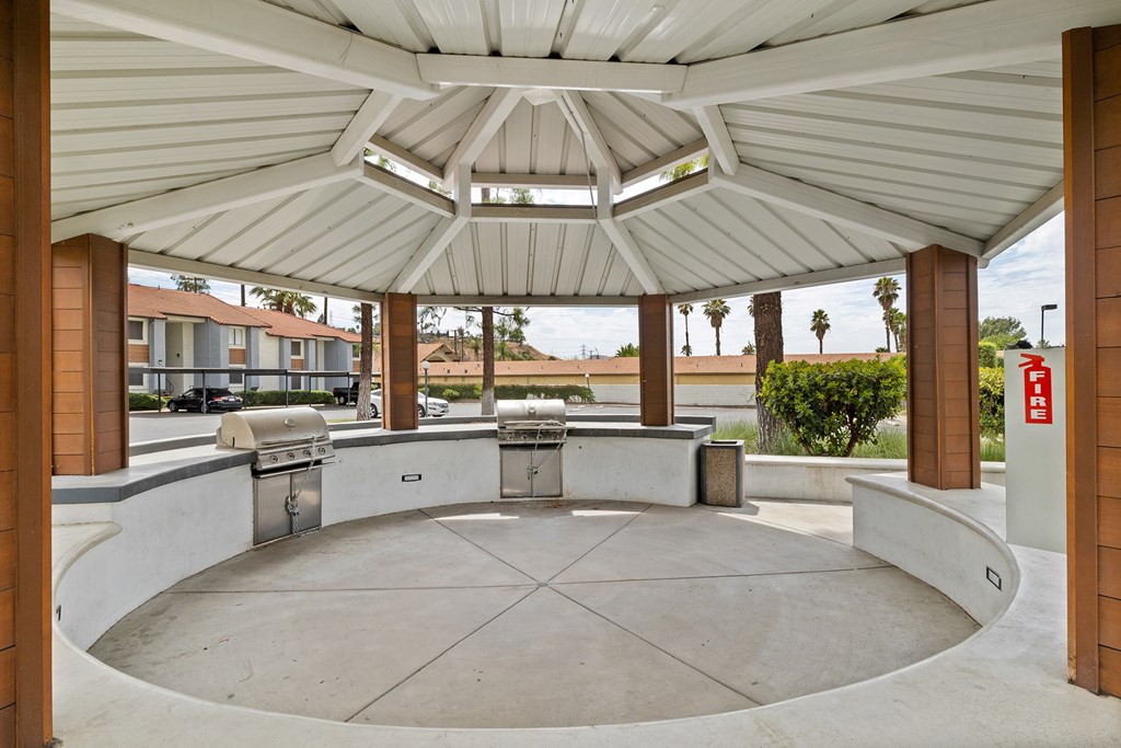 a covered patio with a grill and two bbq grills