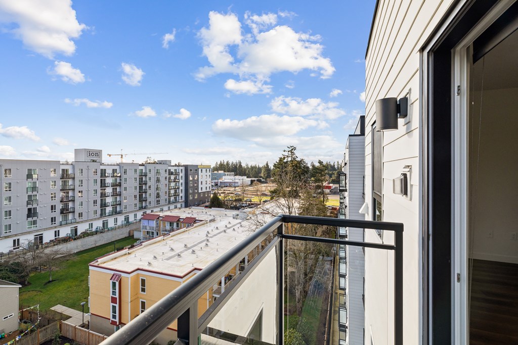 A balcony overlooks a residential area with apartment buildings at Two 10 by Vintage, Shoreline, WA