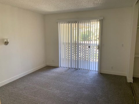 A room with a carpeted floor and a window with blinds.at OTAVON APARTMENTS, Novato, CA