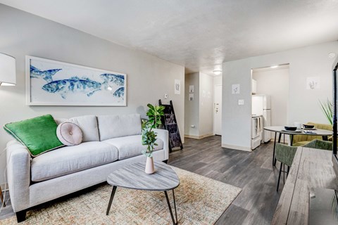 A living room with a grey couch, a coffee table, and a painting of fish on the wall.