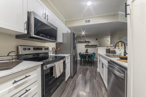 an open kitchen with stainless steel appliances and a dining room with a table