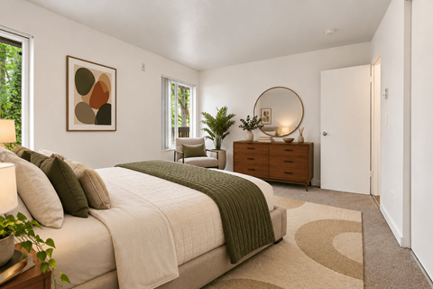 A bedroom with a large bed and a round mirror on the dresser.