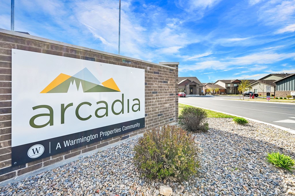A sign for Arcadia, a Warminston Properties Community, is displayed in front of a building.