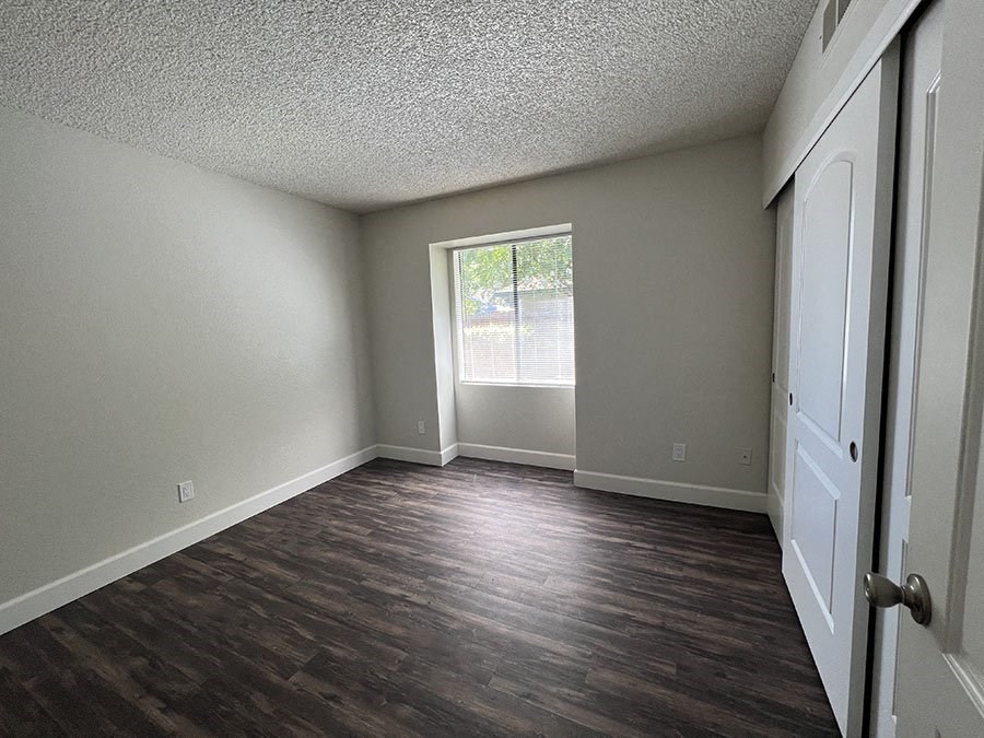 an empty living room with wood floors and a window