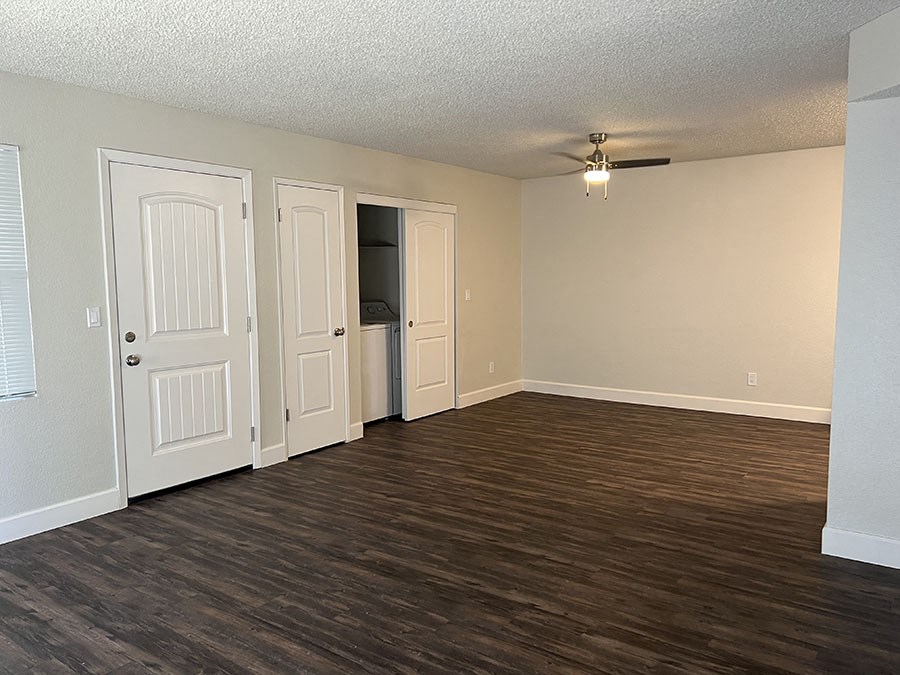 an empty living room with wood floors and a ceiling fan