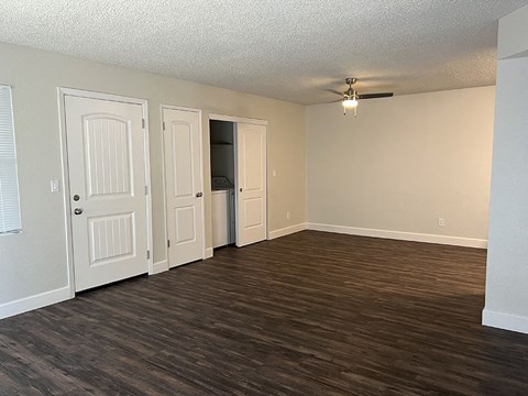an empty living room with wood floors and a ceiling fan