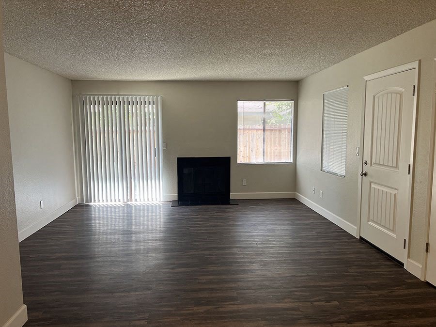 an empty living room with wood floors and a fireplace