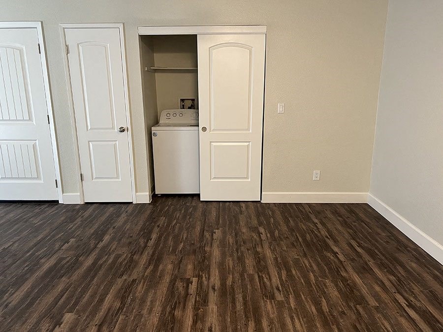 a room with wood floors and a refrigerator and a closet