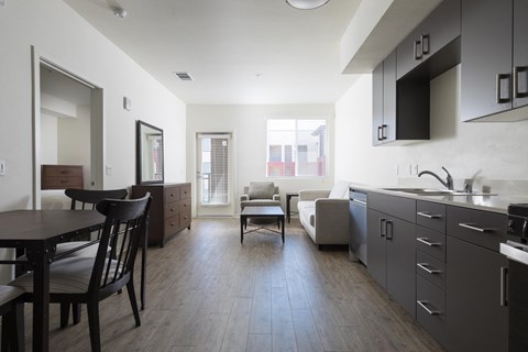 A modern kitchen with dark wood floors and furniture.