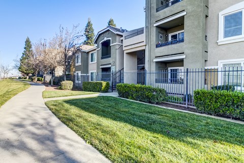 A residential building with a well-maintained lawn and a sidewalk at AGAVE APARTMENTS, Elk Grove, CA
