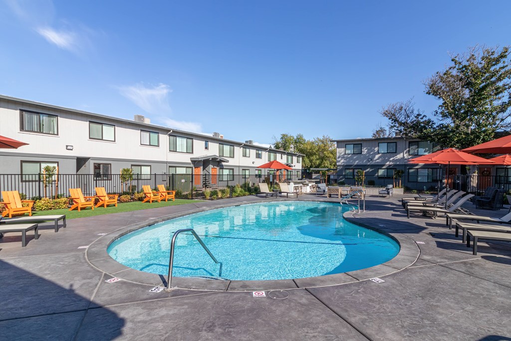 Apartments in Downtown Sacramento CA For Rent - Mode - Fenced In Pool Area Surrounded By Lounge Chairs And Umbrellas With The Apartments In The Background
