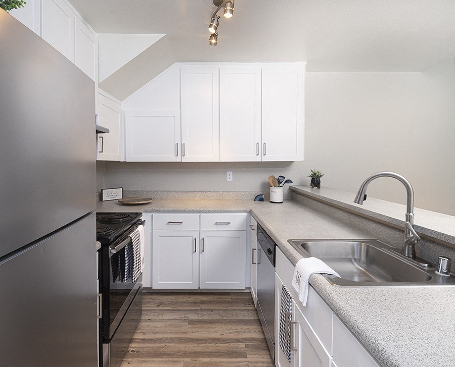 Rohnert Park CA Apartments - Americana - Galley Kitchen with White Cabinets, Marble Countertops, and Stainless Steel Appliances