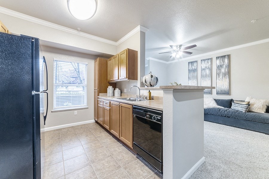 an open kitchen and living room with a refrigerator and a sink